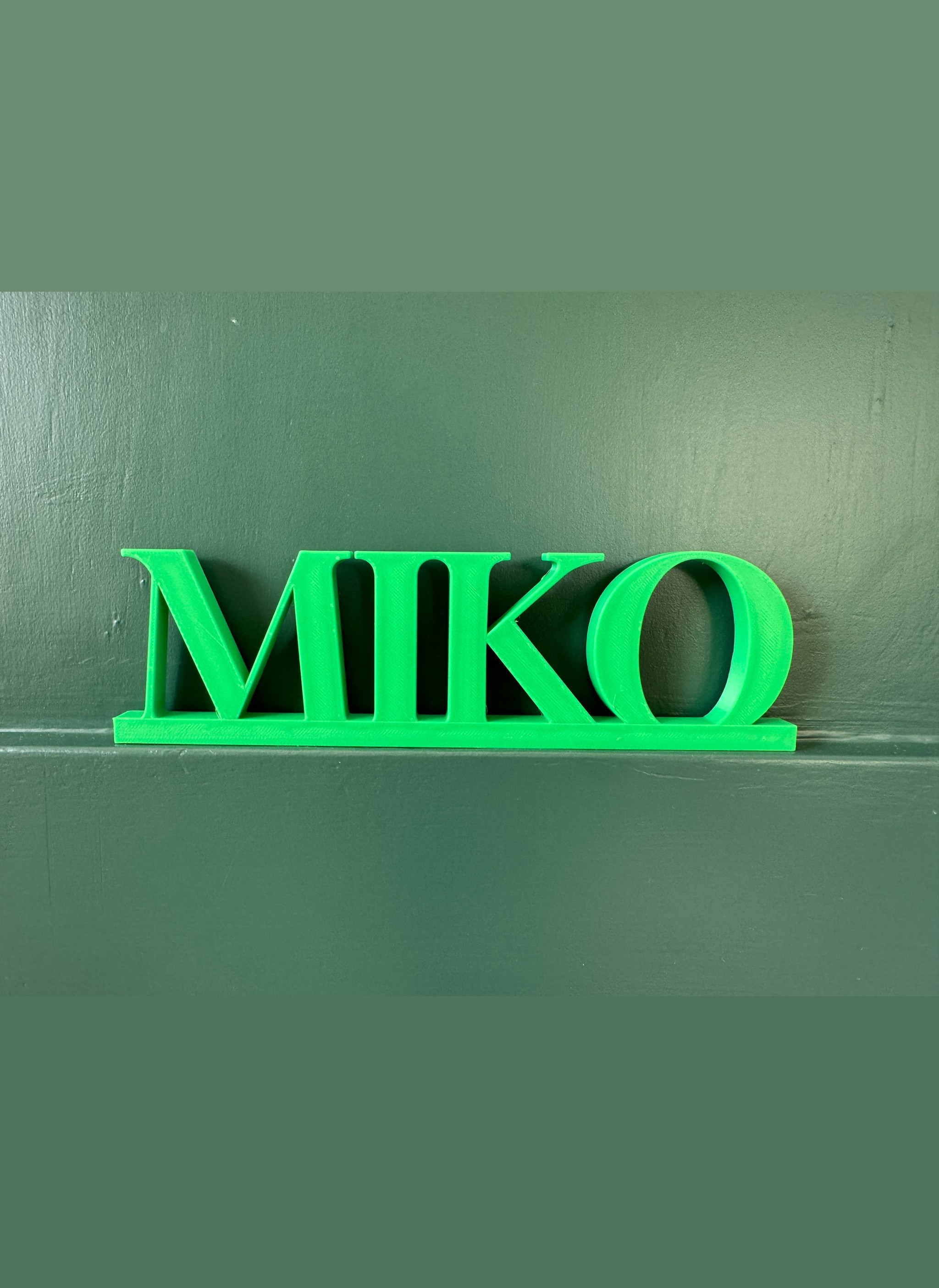 MIKO, a 3D-printed name in green on a shelf
